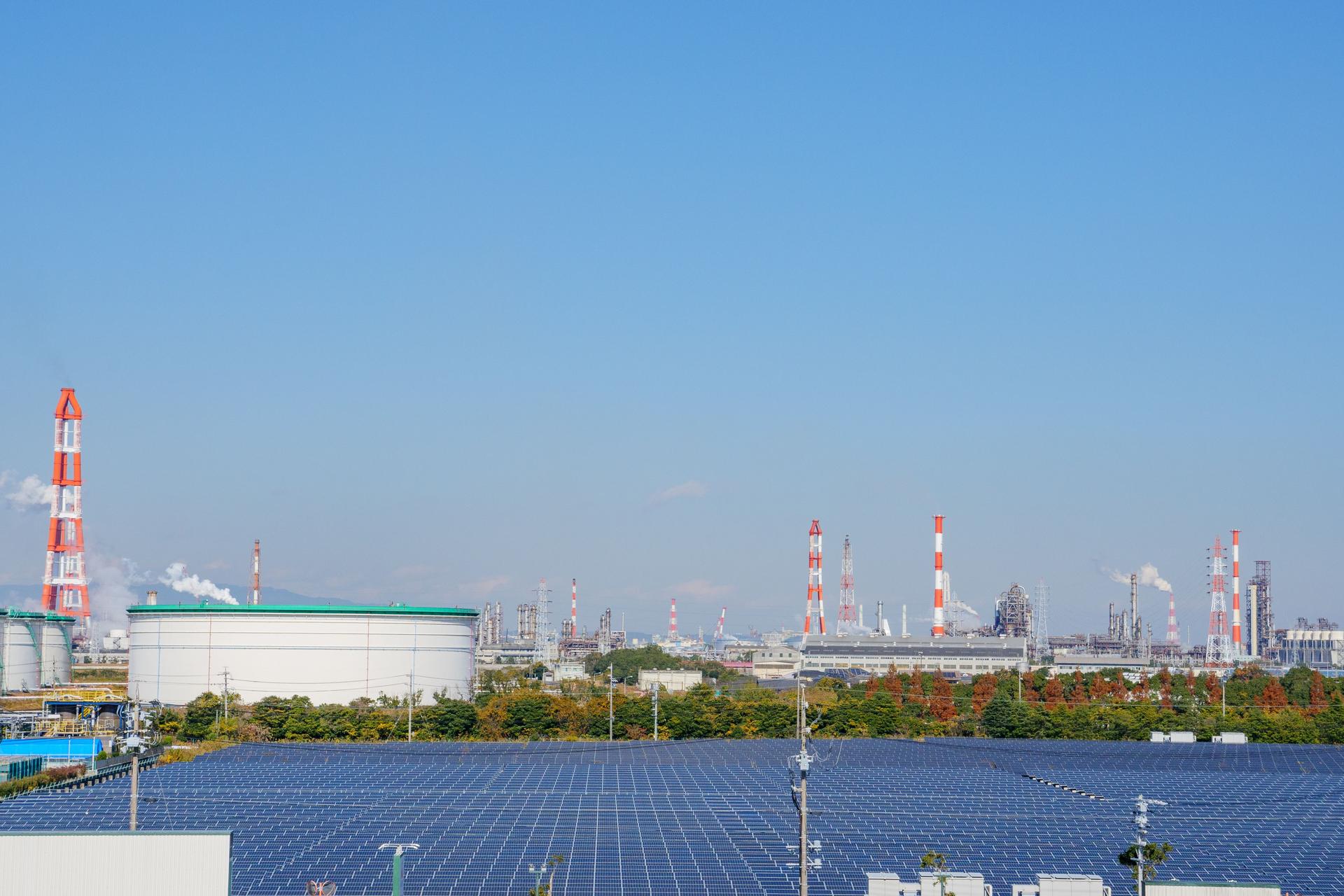 Kontrast zwischen Sonnenkollektoren und Schornsteinen in petrochemischen Anlagen