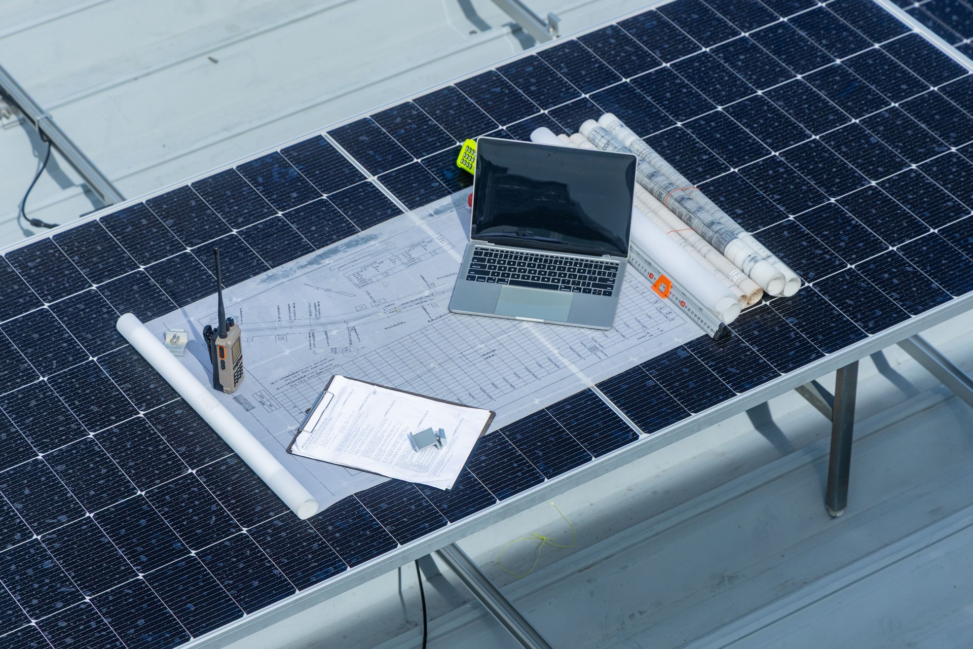 Laptop und Blaupausen auf Solarpanel-Workstation